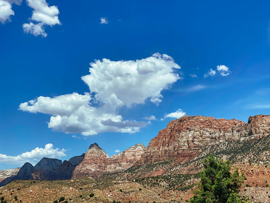 brown rocky mountain under blue sky and white clouds during daytime